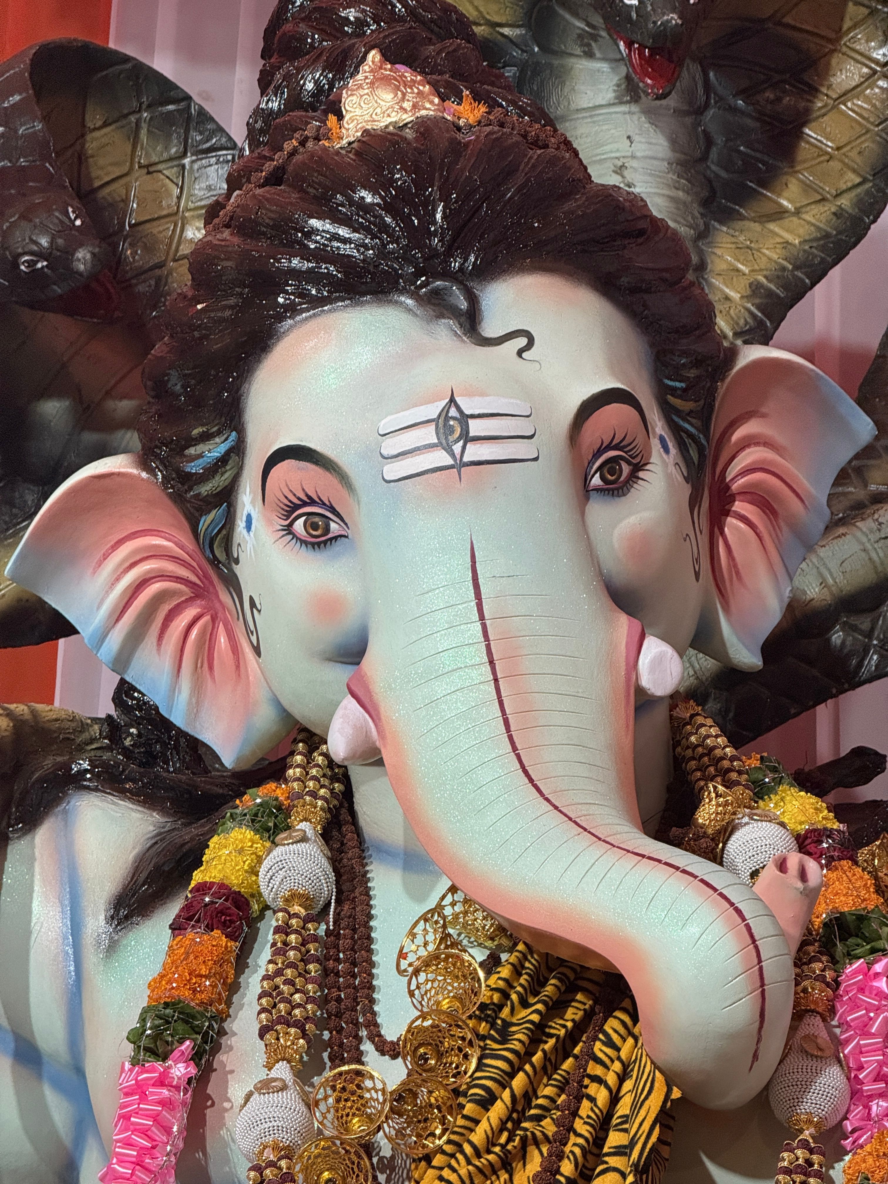 Close-up of a detailed Ganesh idol adorned with vibrant garlands.