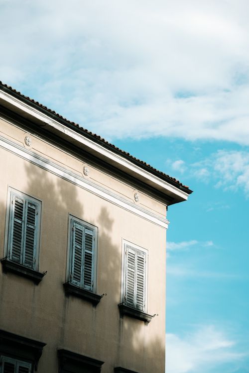 Free A vintage Croatian building facade with shutters casting shadows under a clear blue sky. Stock Photo