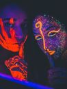 这幅引人注目的肖像拍摄于夜间，描绘了两个涂着霓虹灯脸的女人，在黑暗中闪闪发光
