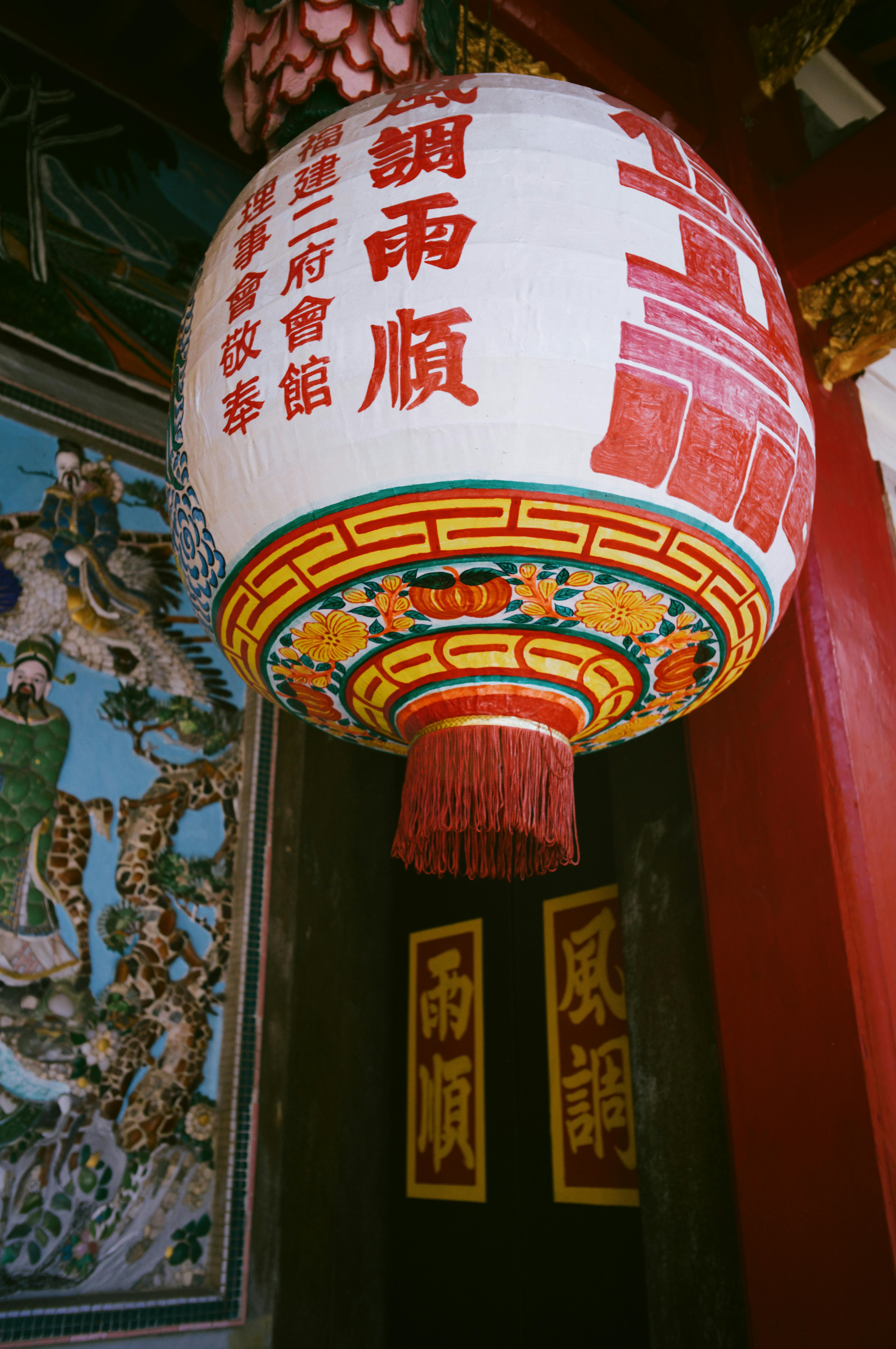 Colorful Chinese lantern with intricate patterns hanging in a traditional temple.