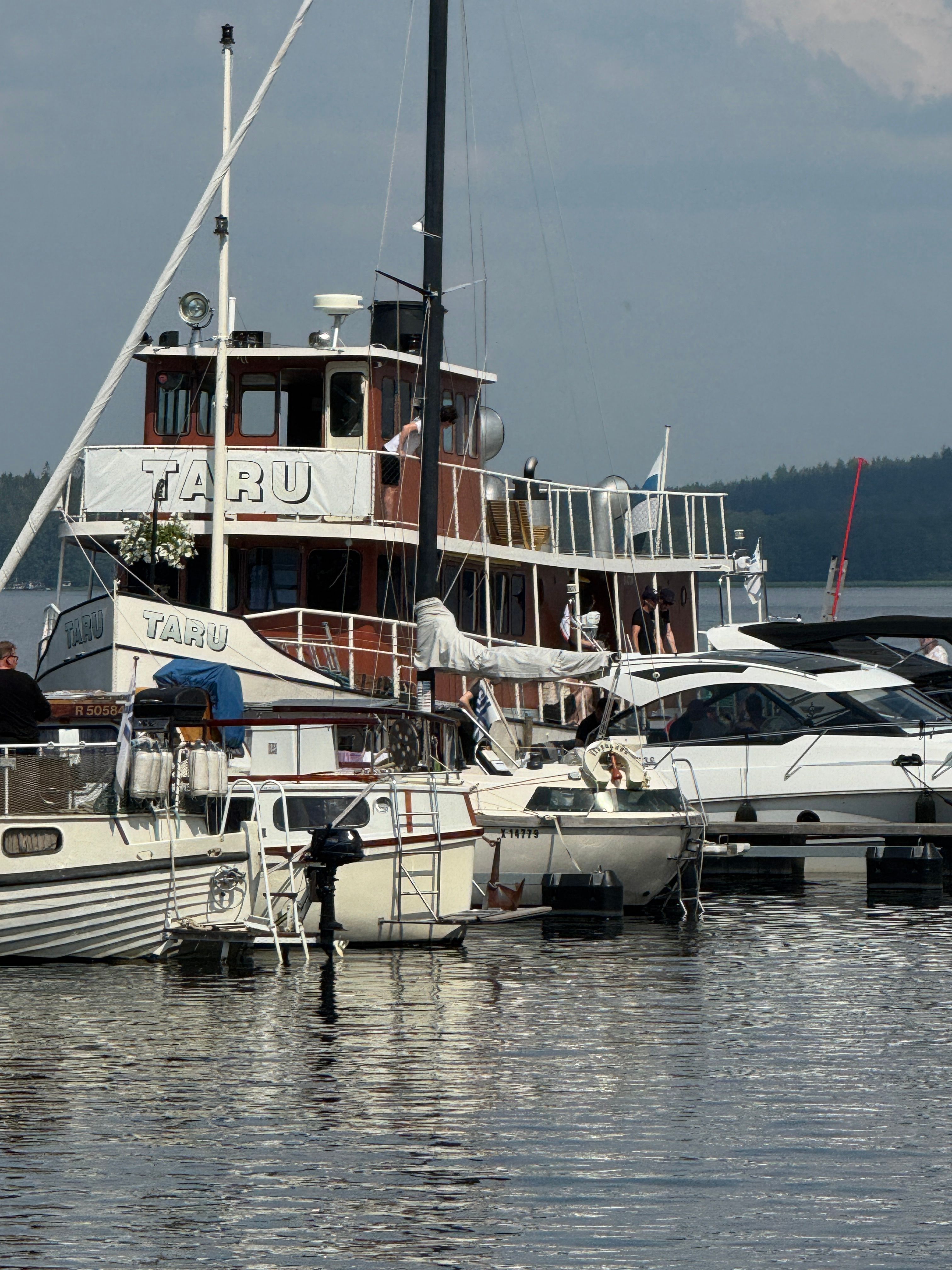 A classic wooden ship docked alongside modern yachts in a serene harbor.