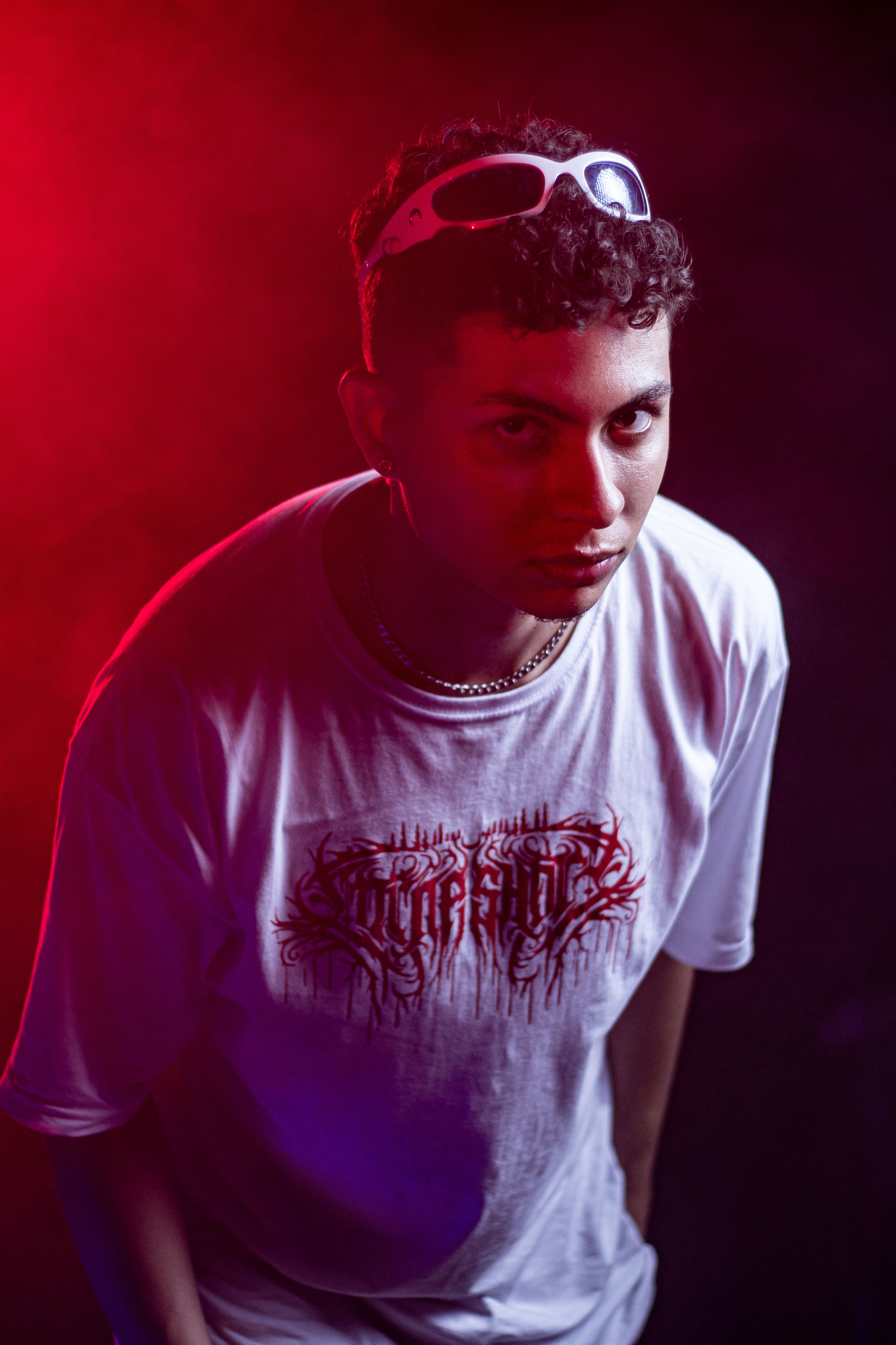 Creative portrait of a young man with sunglasses in dramatic lighting, featuring vivid colors and artistic expression.