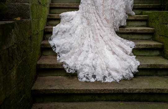 Beautiful lace wedding dress gracefully draped on stone steps, creating a romantic atmosphere.
