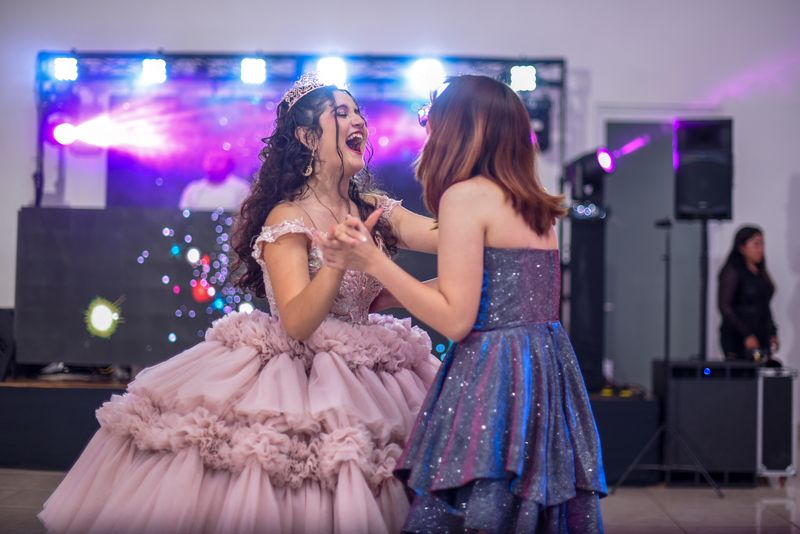 Joyful quinceanera dancing with friends during the reception celebration