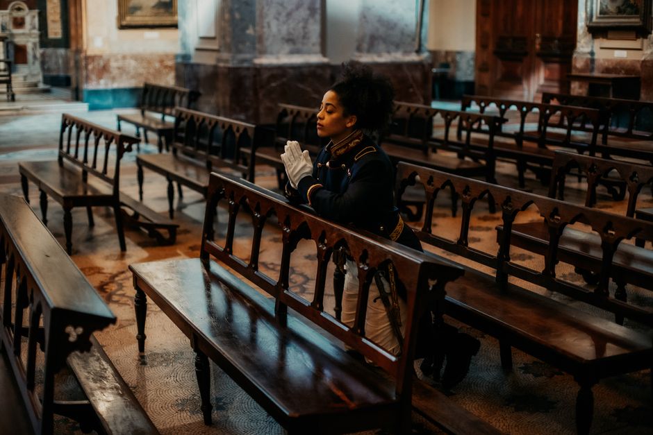 A woman in elegant attire kneels in prayer inside a historic church in Buenos Aires, Argentina.