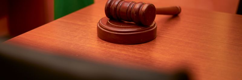 A close-up of a gavel on a courtroom desk representing law and justice.