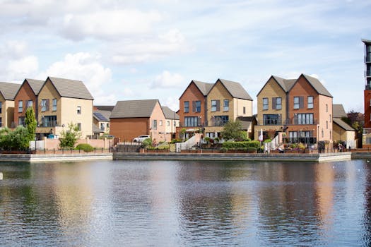 Row of modern houses by a lake with clear reflections and blue sky.