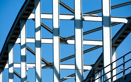 Close-up van het geometrische framewerk van een stalen brug tegen een helderblauwe lucht. Hier ziet u de moderne architectuur.