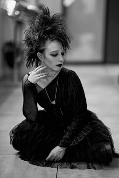 Chic gothic style portrait of a woman sitting indoors in black and white.