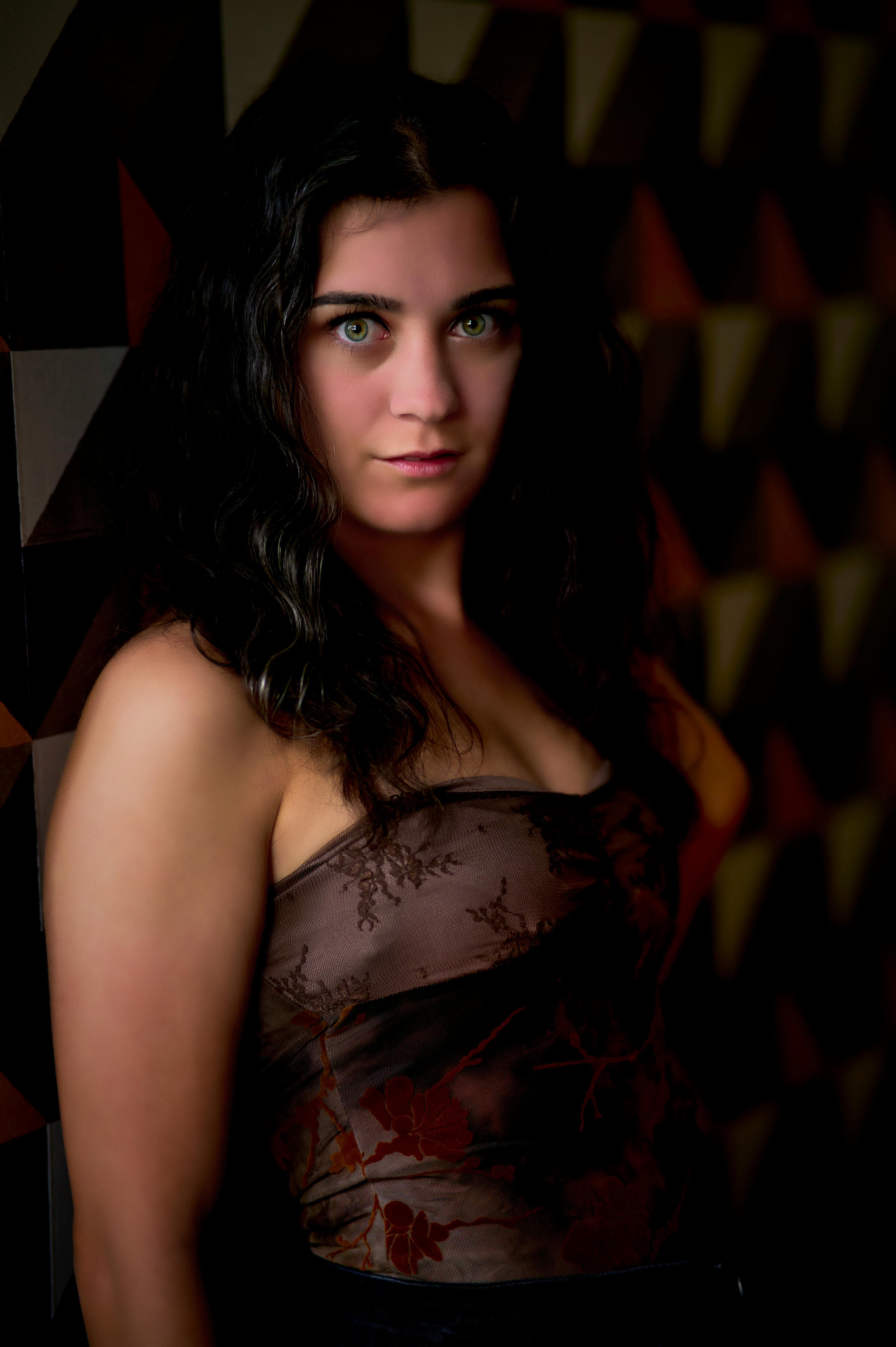 这幅肖像画描绘了一位优雅的女子，她有着绿色的眼眸，在几何形状的背景前摆出了姿势