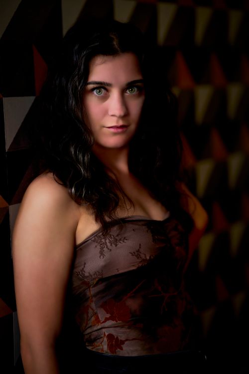 Free A striking portrait of an elegant woman with green eyes, posed against a geometric background. Stock Photo