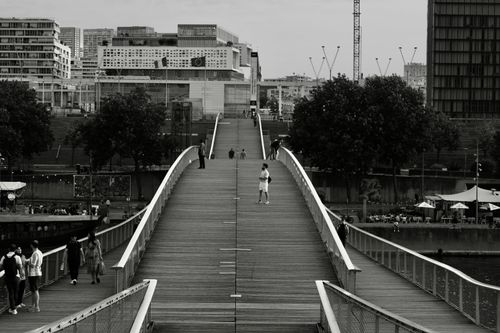 Free A monochrome view of a Parisian bridge bustling with people, capturing urban life. Stock Photo