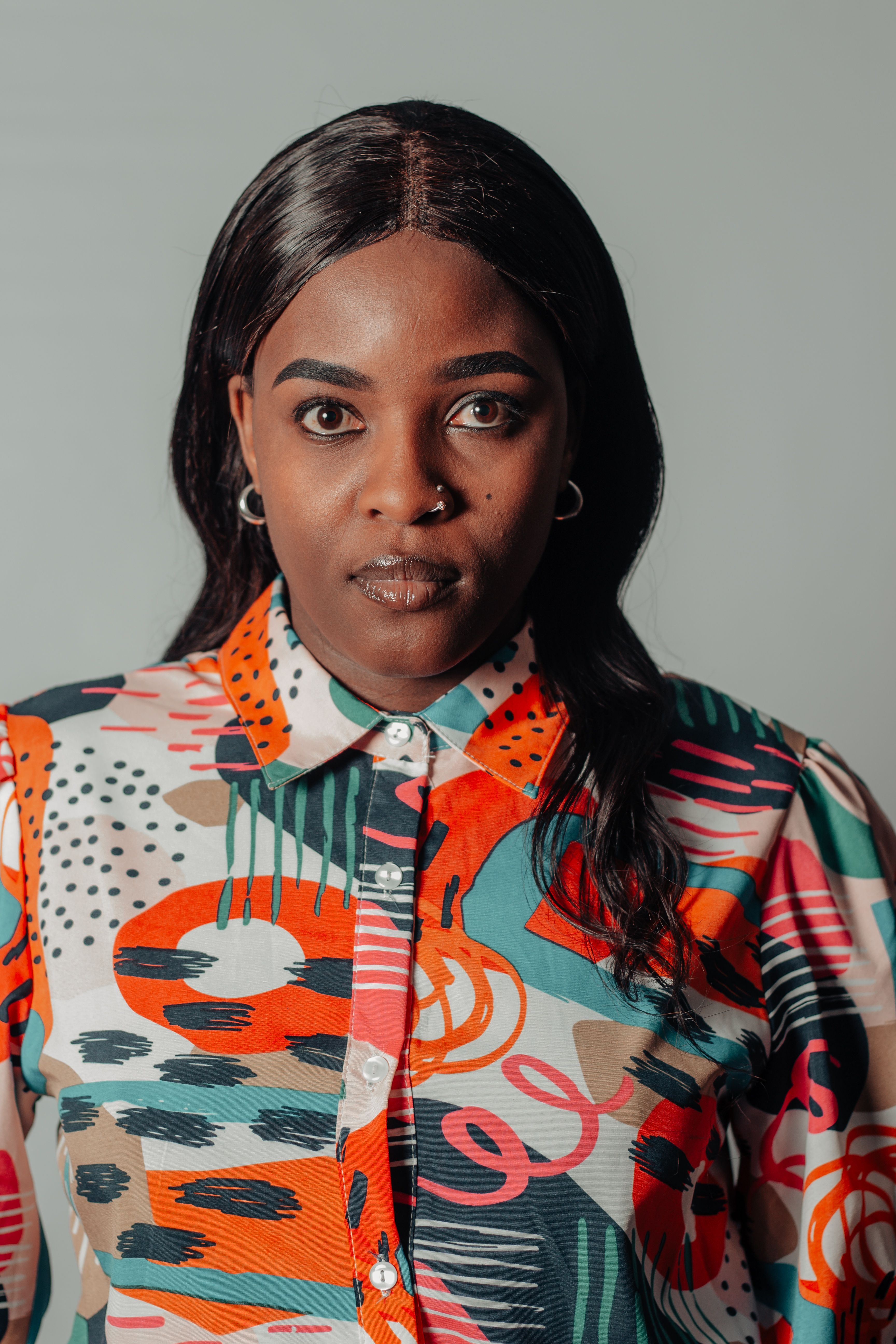 Portrait of a woman in a vibrant patterned shirt with a neutral background.