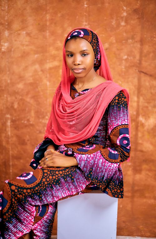 Free Portrait of a woman in vibrant traditional attire with a coral veil, warm tones. Stock Photo