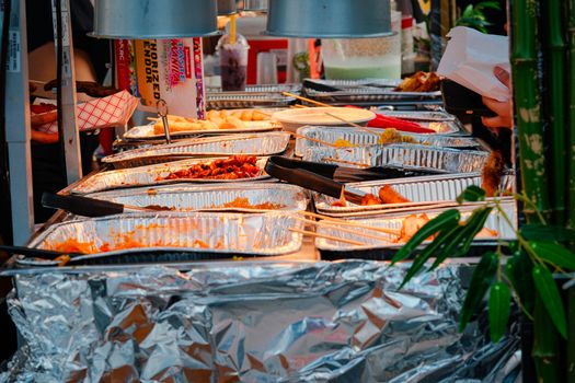 Explore a diverse range of delicious Asian street food at a bustling outdoor market stall.