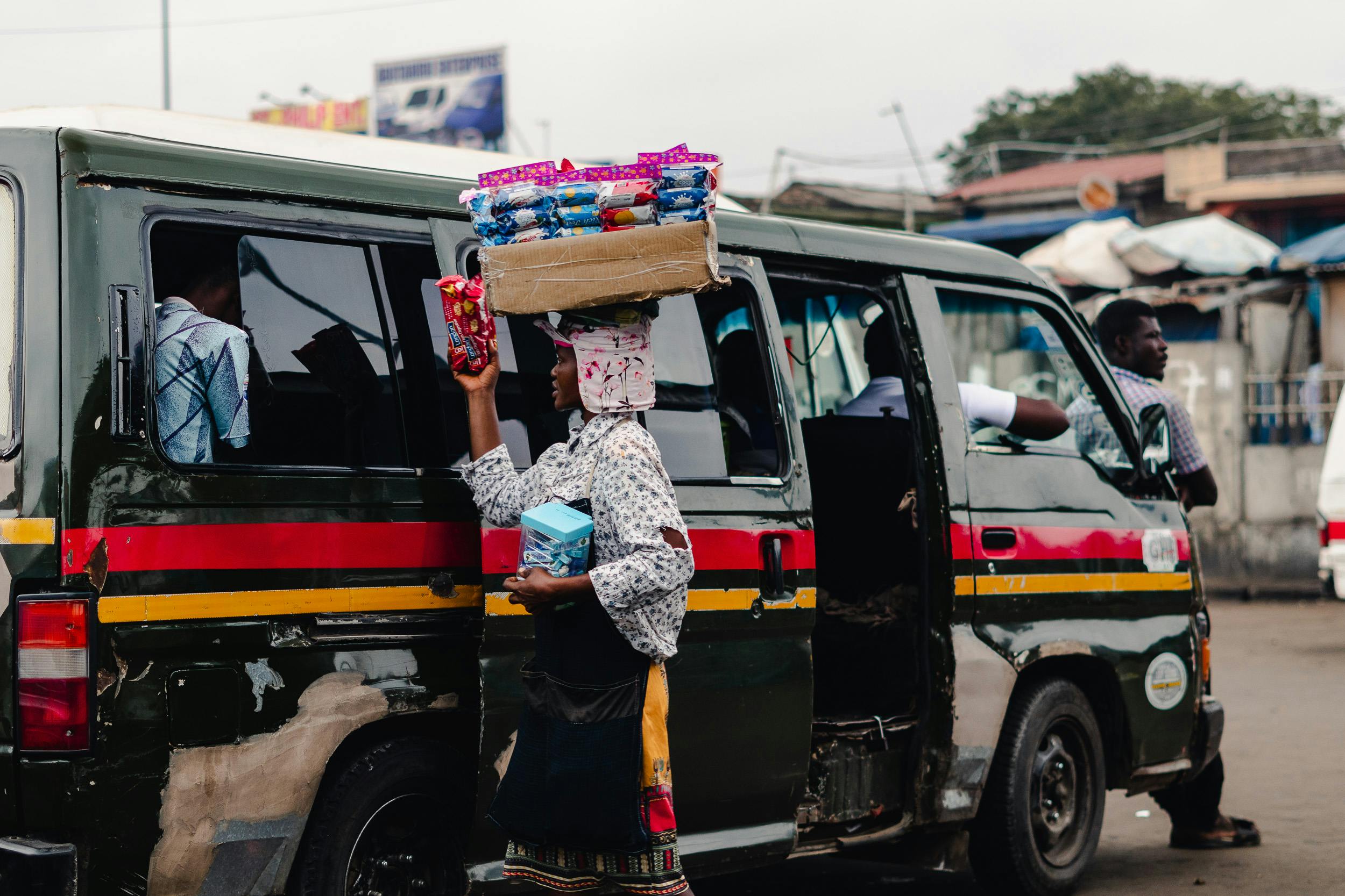 A bustling scene of a street vendor selling snacks to trotro passengers in vibrant Ghana.