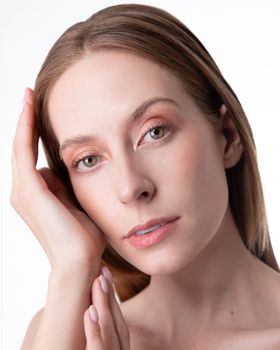 Close-up portrait of a woman with a serene expression and subtle makeup on a white background.