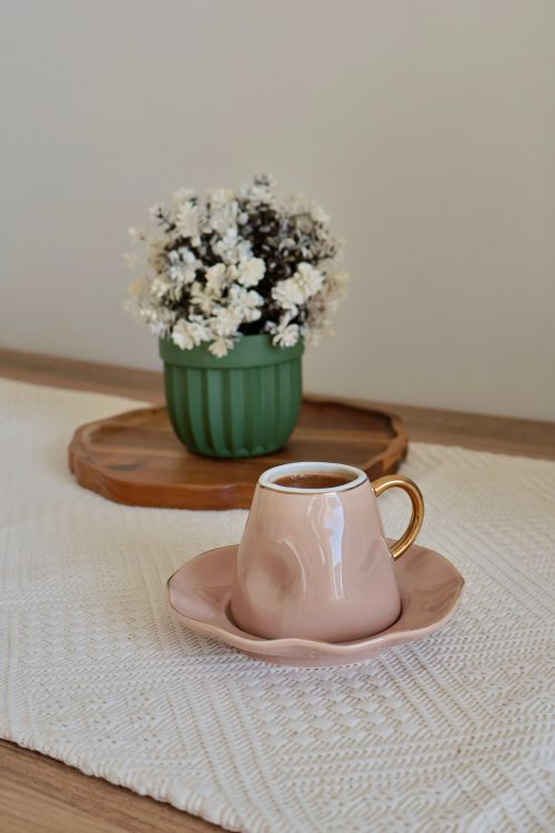 Free Chic pink coffee cup on saucer with flowers in a green vase for a stylish look. Stock Photo