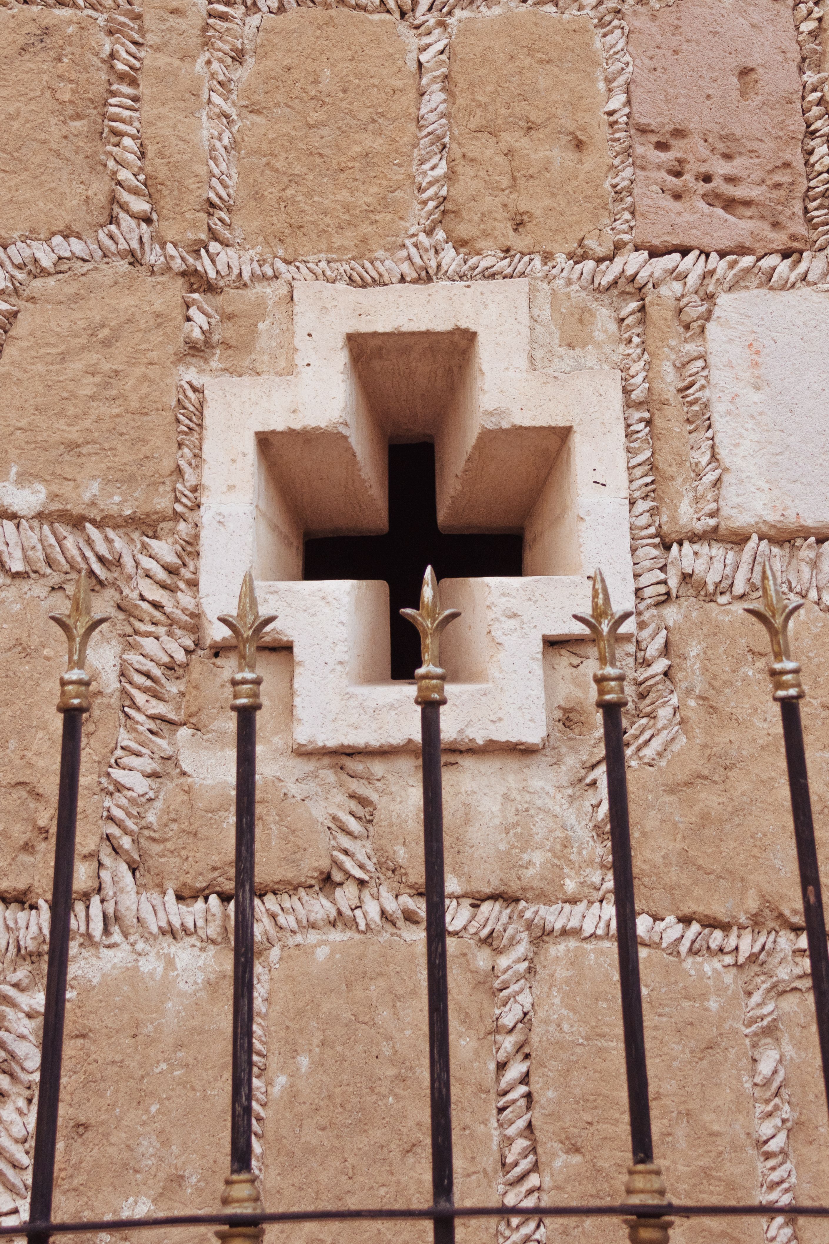 Close-up of a stone cross-shaped window on a historic building in Aguascalientes, Mexico.