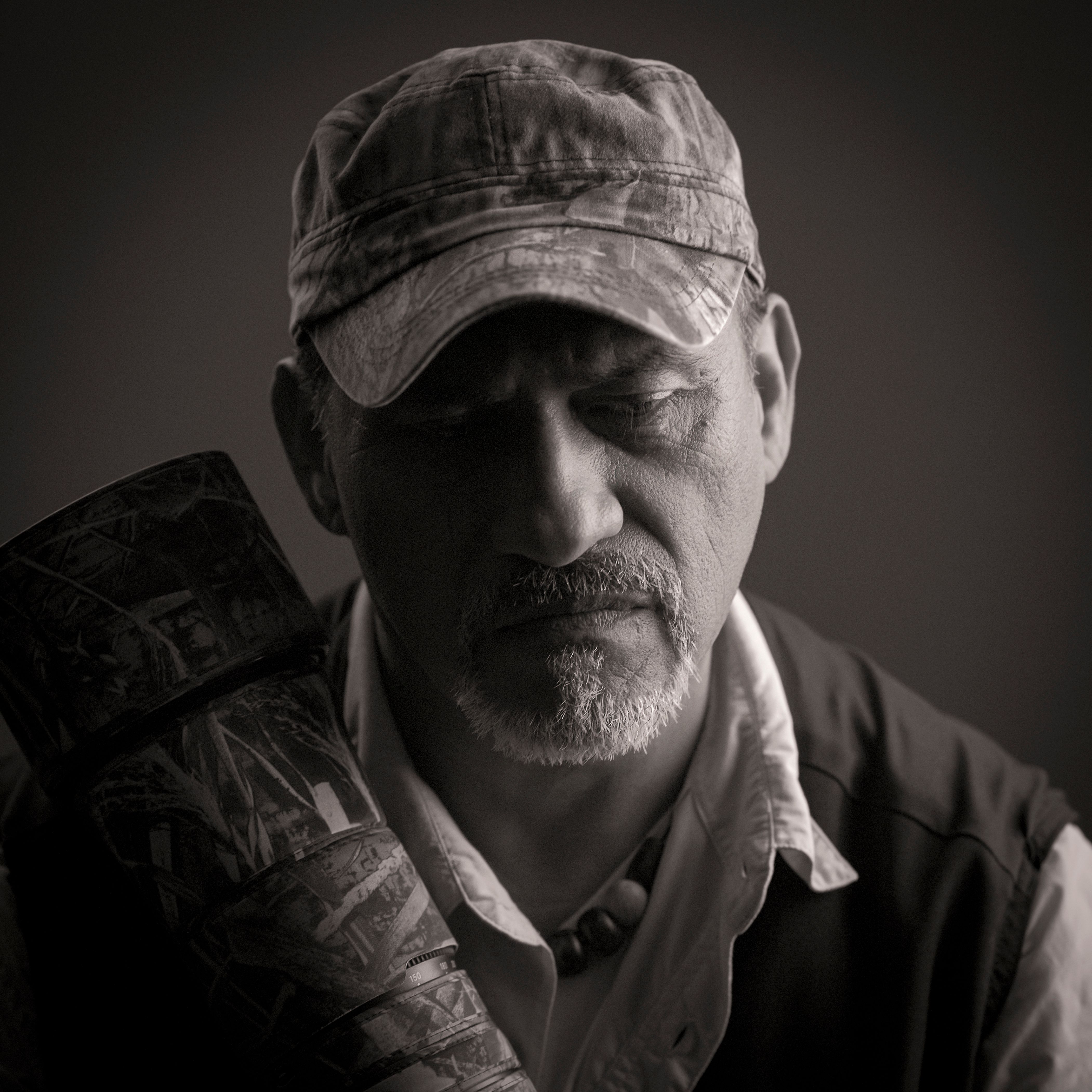 Black and white portrait of a mature male photographer with a camera