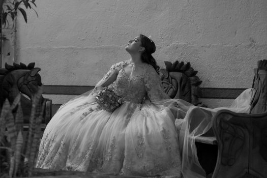 A bride in a vintage gown poses serenely indoors, exuding elegance and charm.