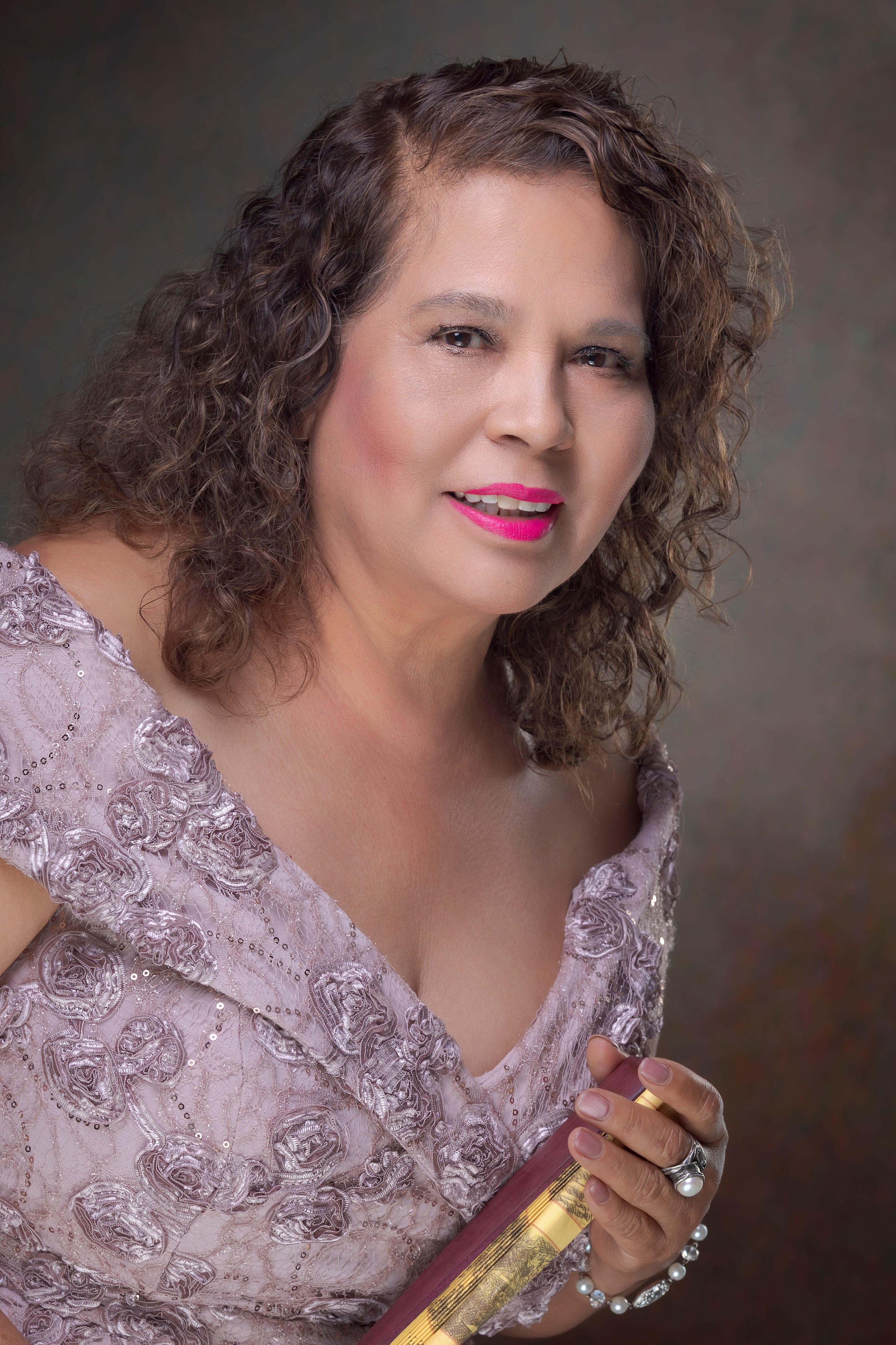 Sophisticated portrait of an adult woman in a floral pink dress with curly hair.