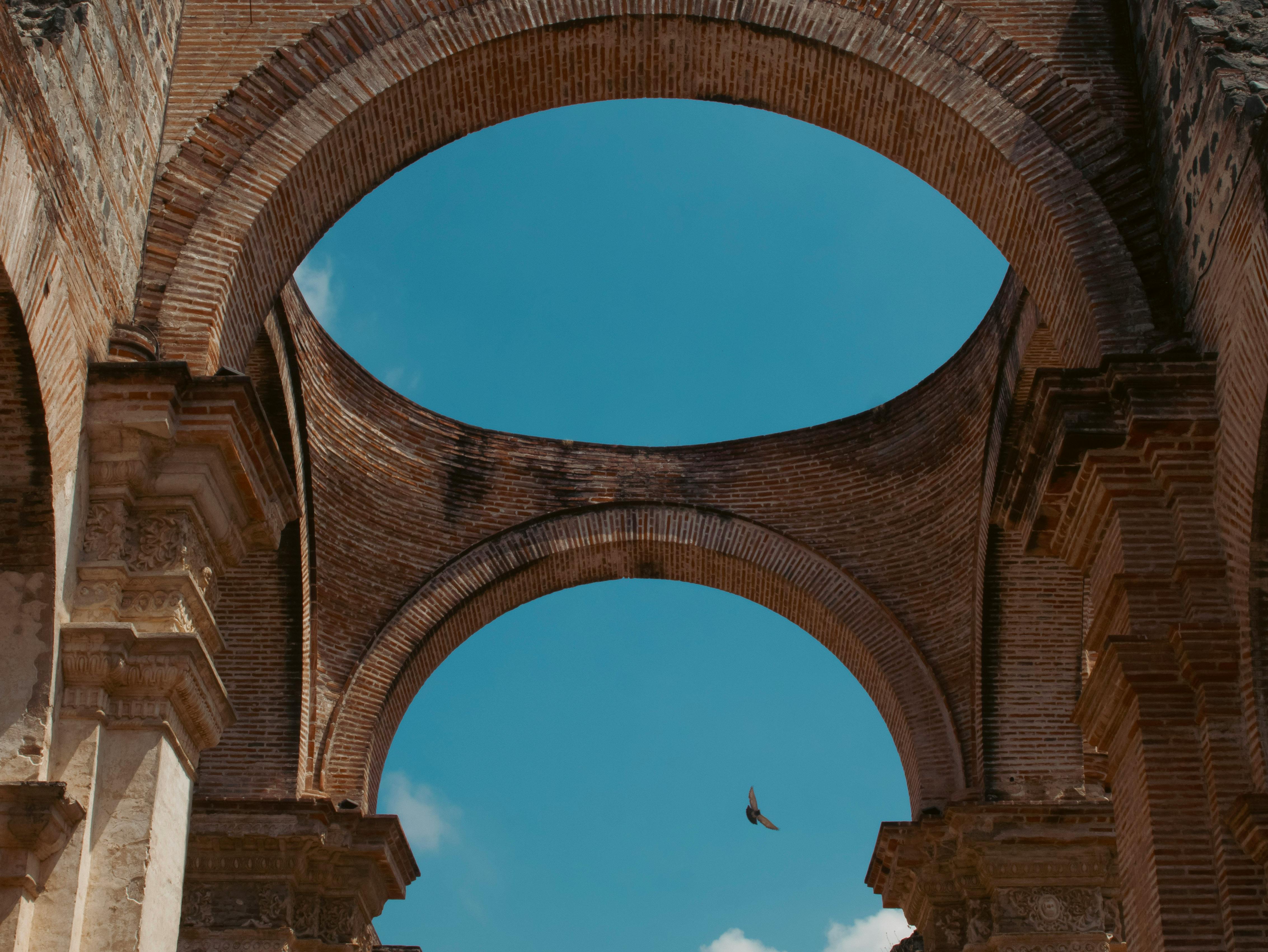 Elegant ancient brick arches of a historic ruin in Antígua, Guatemala, under a clear blue sky. - Antigua