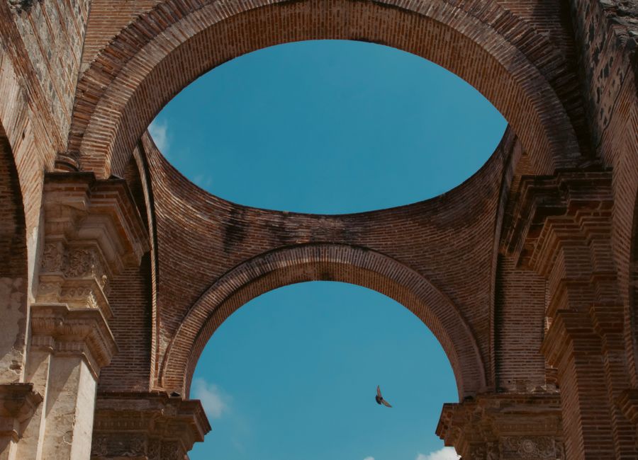 Elegant ancient brick arches of a historic ruin in Antígua, Guatemala, under a clear blue sky.