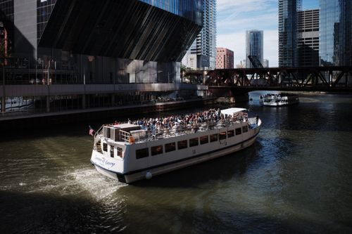 Free A river cruise boat with tourists sailing under city skyscrapers and a bridge. Stock Photo