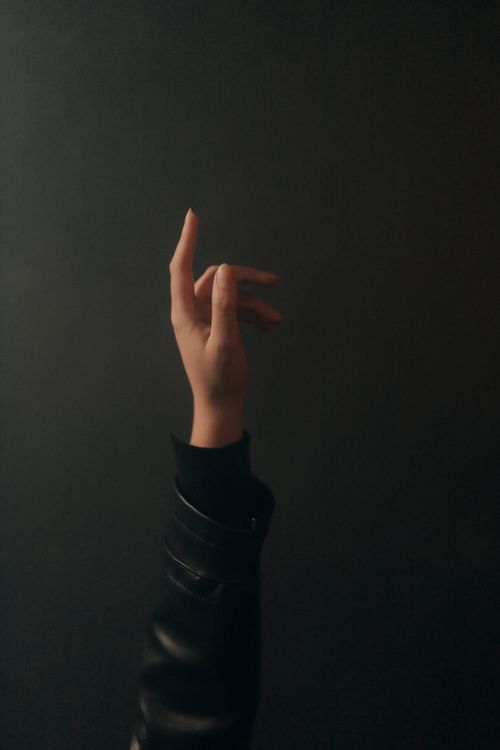 Free Elegant hand in black jacket gesturing against a dark backdrop. Stock Photo
