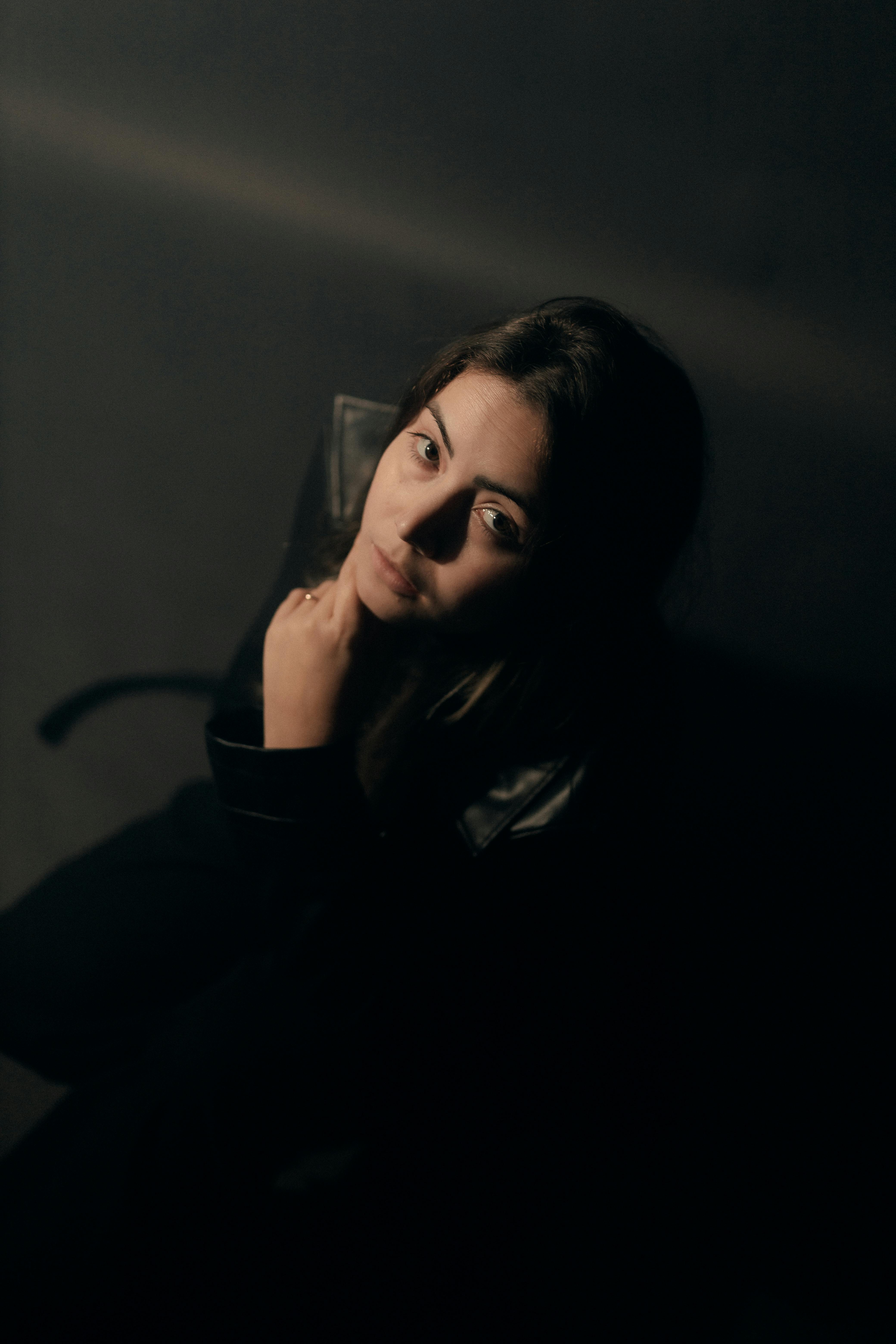 A mysterious portrait of a woman in dark, moody lighting, conveying introspection.