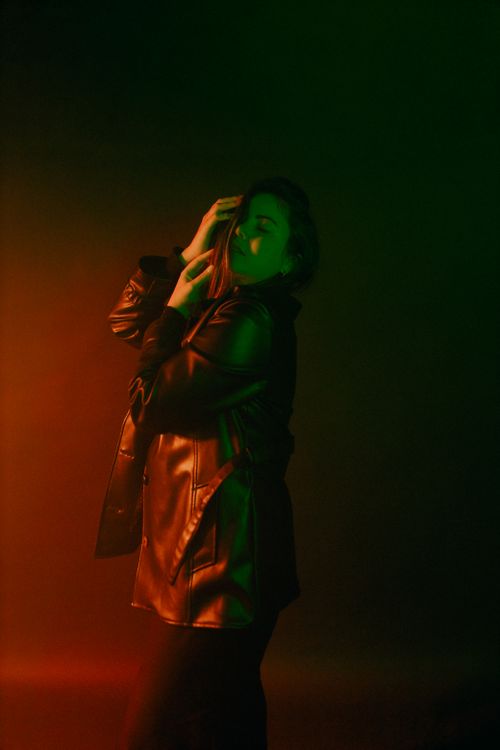 Free Artistic portrait of a person in leather jacket under vivid green and red lighting. Stock Photo