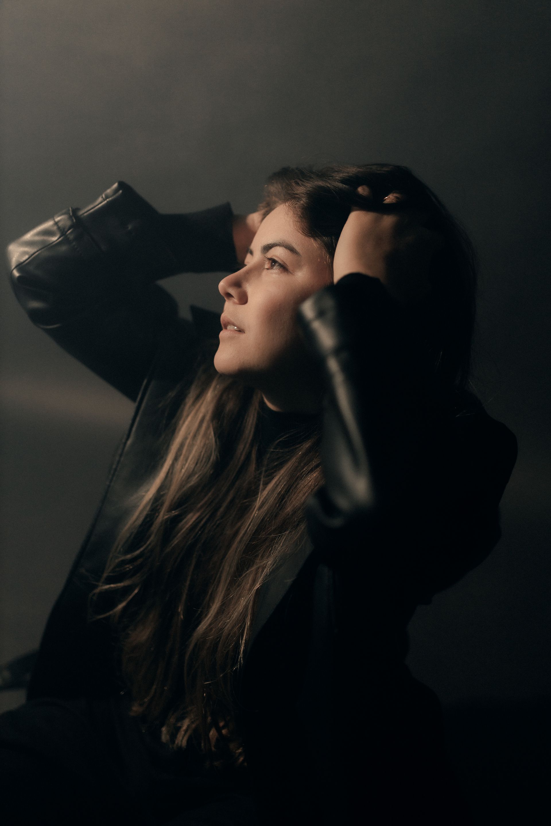 Profile shot of a woman in a leather jacket in a moody atmosphere