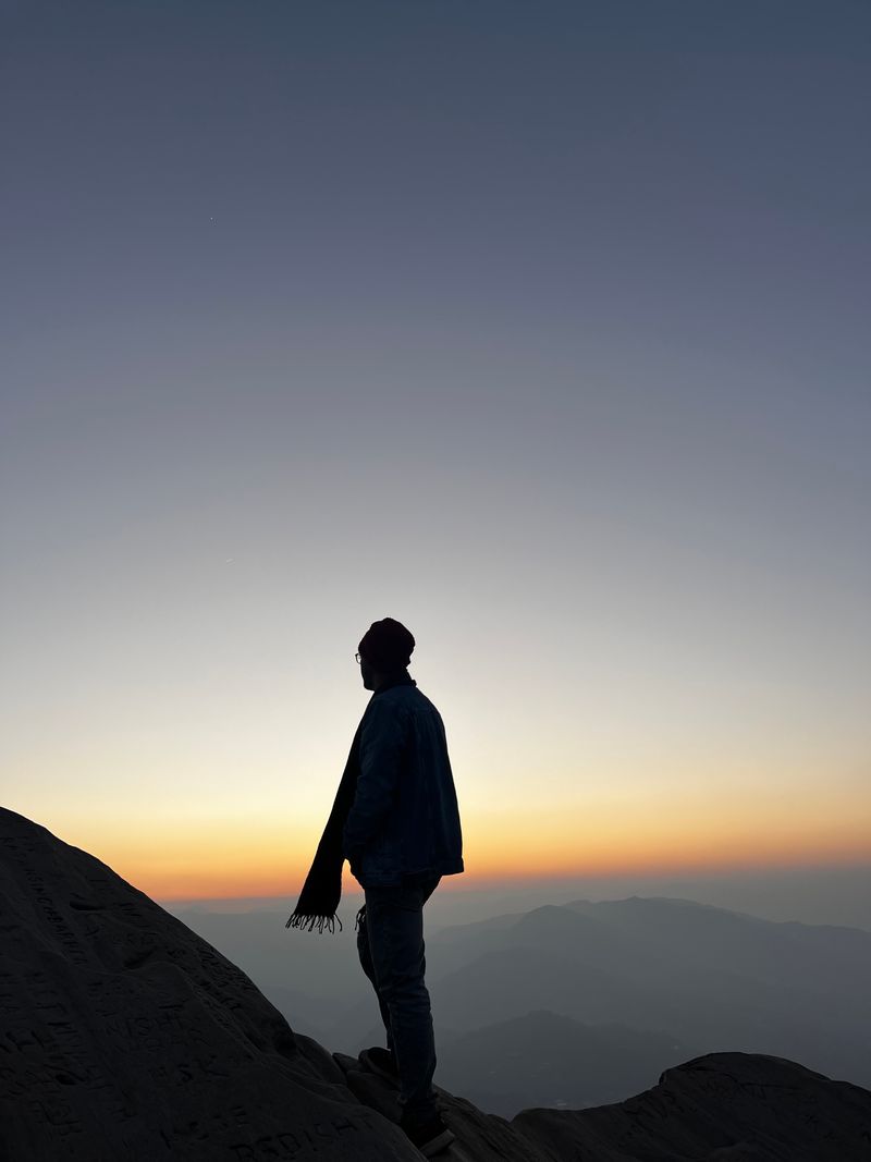 Figure standing at dusk before a mountain ridge — photo by musafirdost08 on Pexels