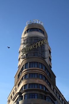 Iconic Capitol Building in Madrid featuring the Schweppes sign under a clear blue sky.