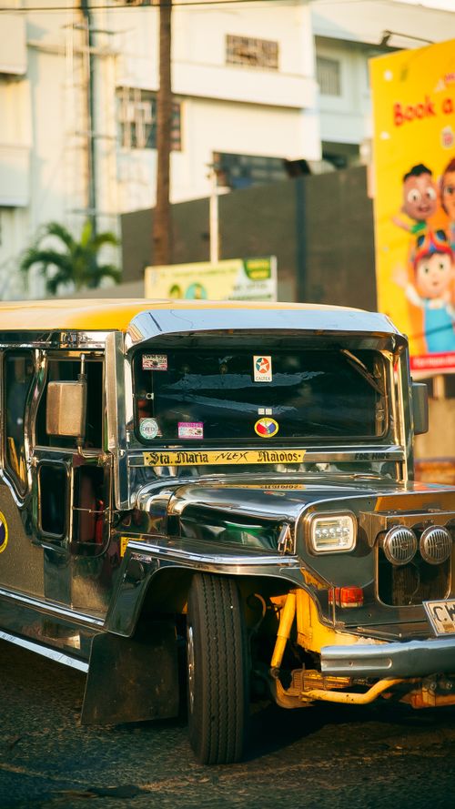 Free A vibrant jeepney parked on a sunny street in the Philippines, showcasing local culture. Stock Photo