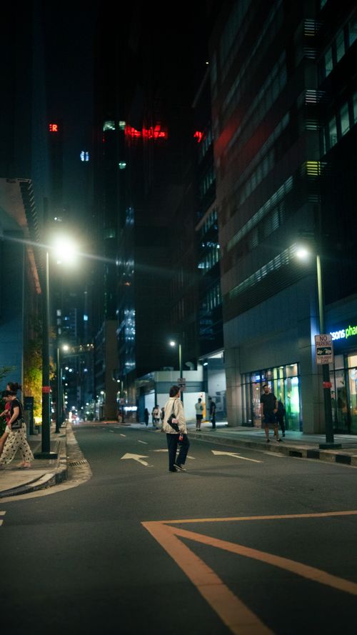 Free A bustling city street at night with people walking, illuminated by streetlights. Stock Photo