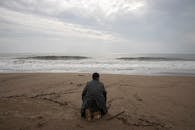 Person Wearing Gray Dress Shirt Sitting on Seashore