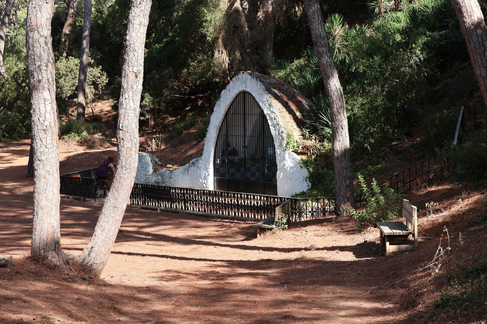 Scenic view of a hermitage nestled in a sunlit pine forest in Puerto Real, Spain.