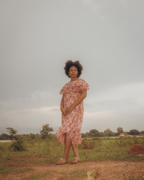 Free A woman in a floral dress standing in a serene outdoor setting, exuding elegance and tranquility. Stock Photo