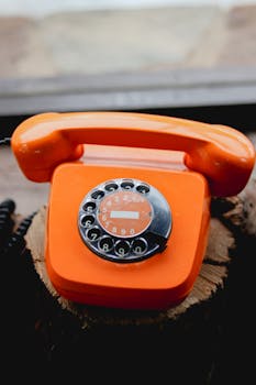 A vibrant orange rotary dial telephone showcasing retro design and vintage appeal.