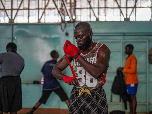 Free A boxer wraps his hands with red tape in a Nairobi gym, preparing for training. Stock Photo