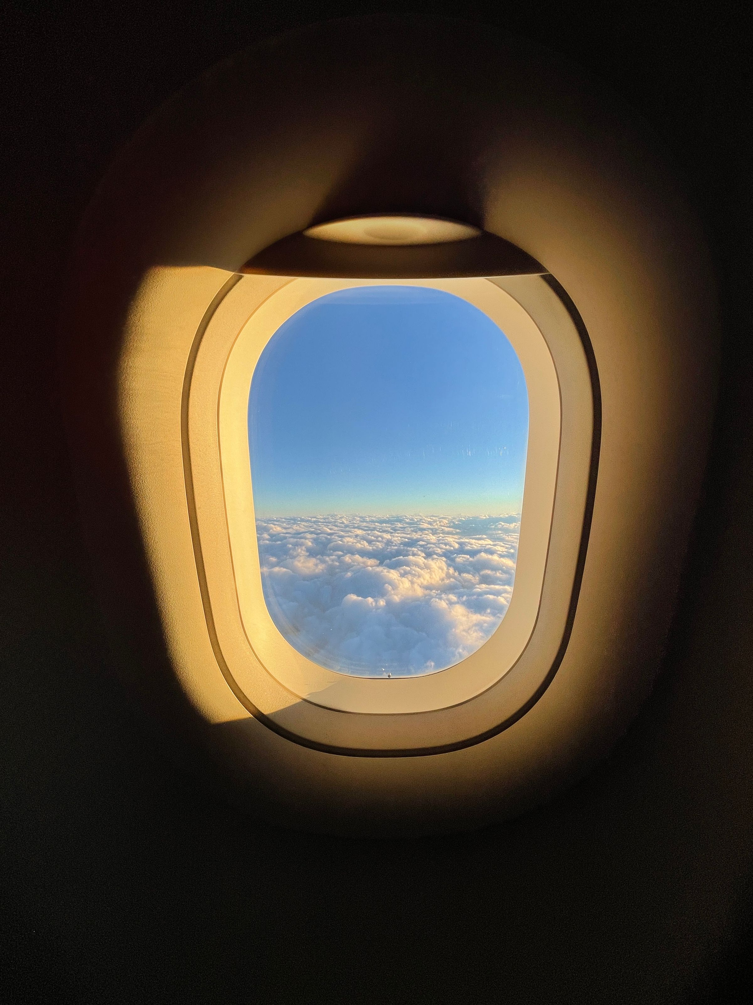 Bright clouds and blue sky seen through an aircraft window at high altitude