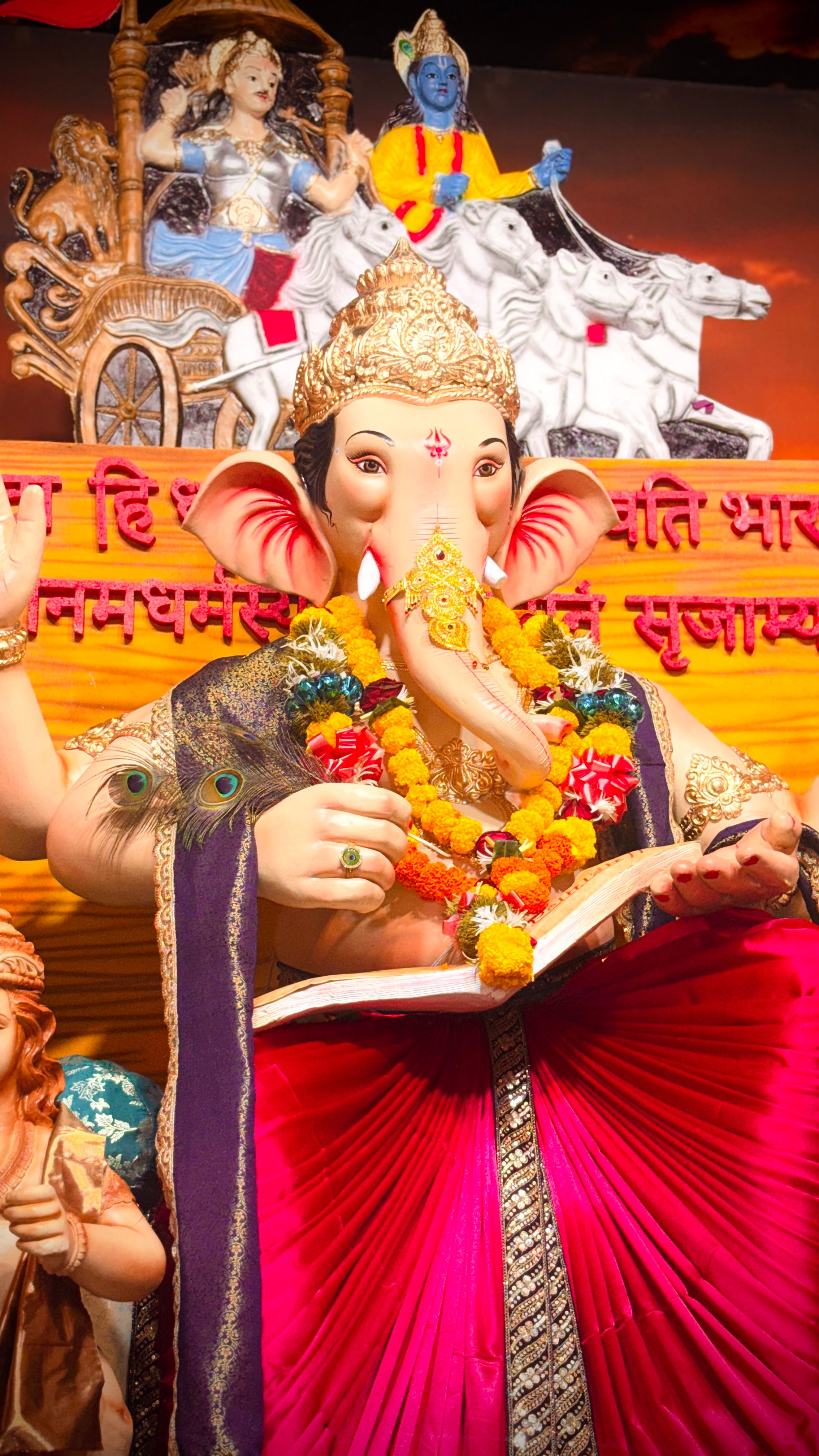 Colorful statue of Lord Ganesh with a vivid mural at a Hindu festival.