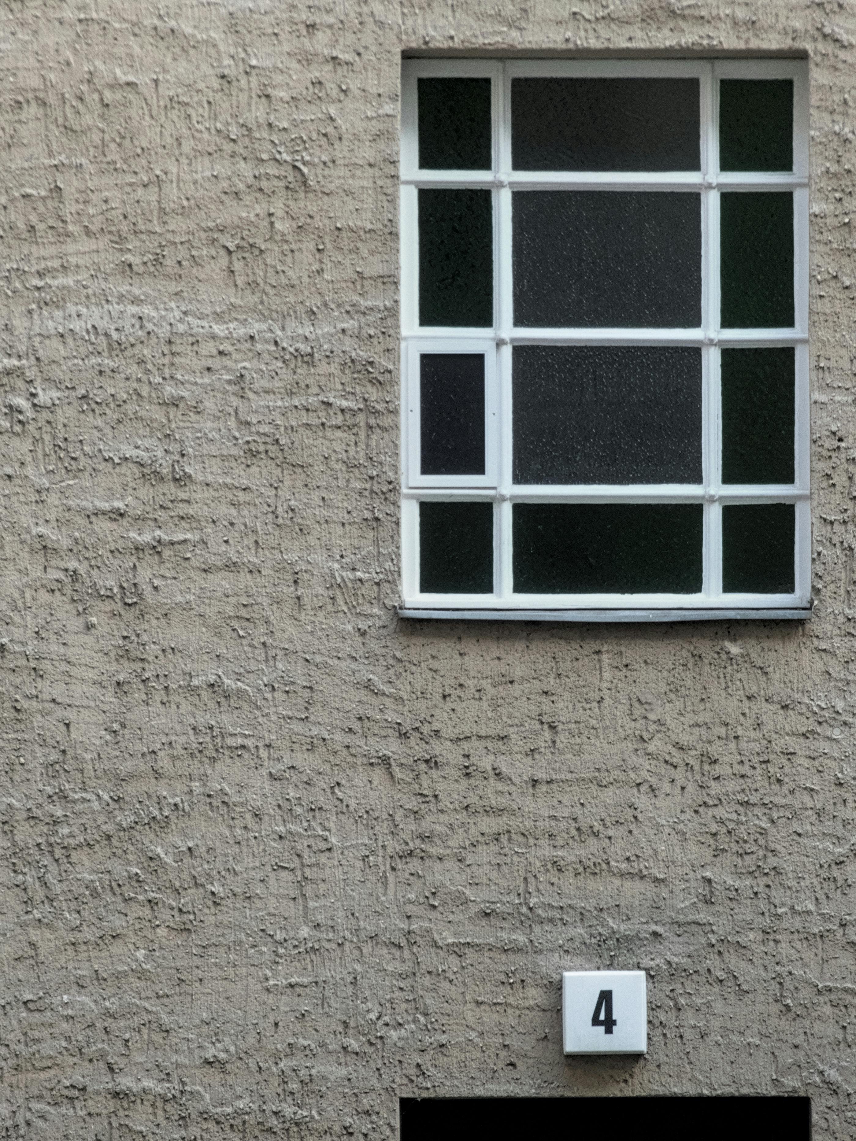 A minimalist composition featuring a grid window on a textured wall with the number four in Berlin, Germany.