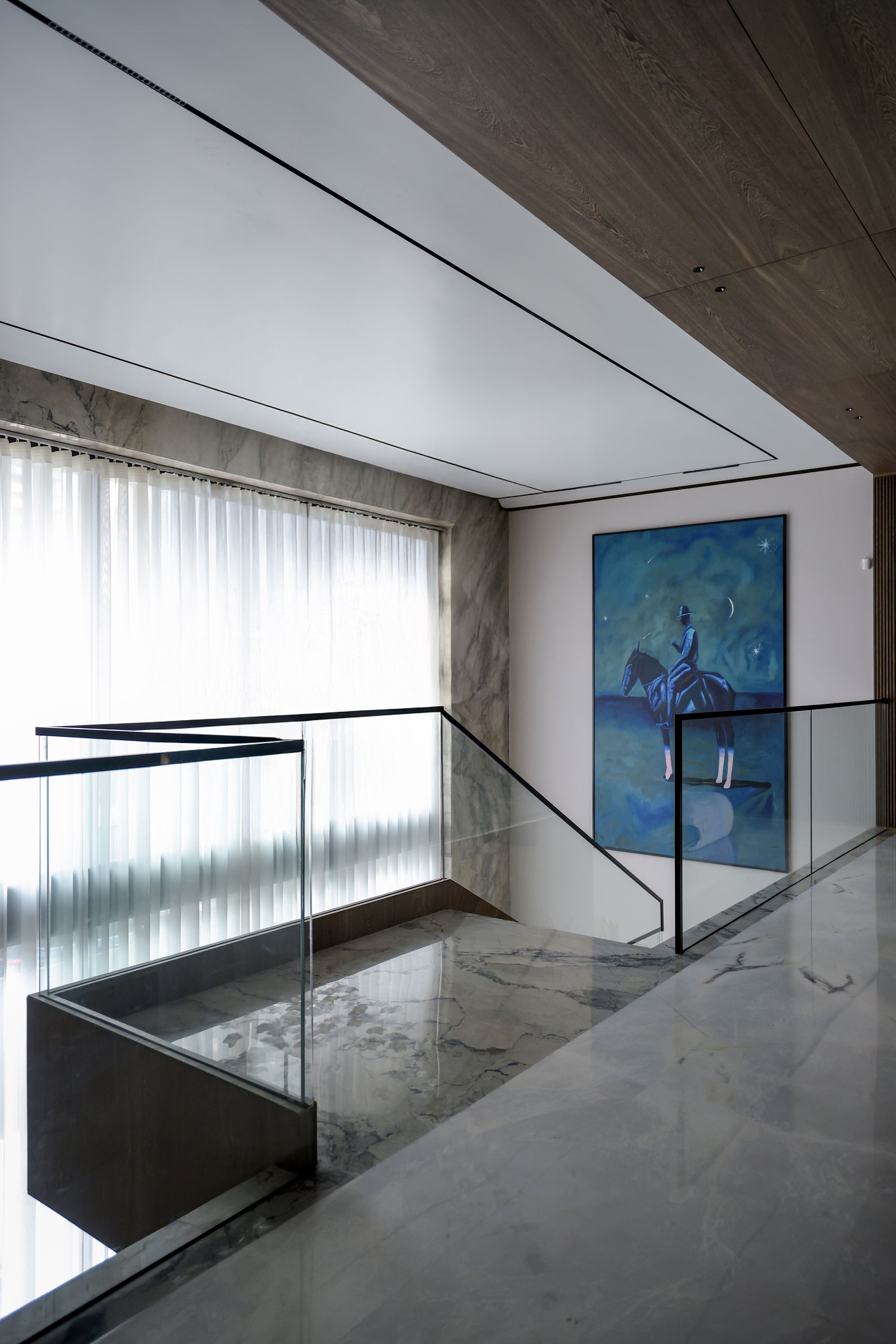 Luxurious modern interior featuring a glass staircase and artistic decor.
