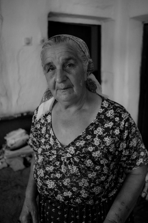 Free Black and white portrait of a senior woman in traditional attire inside a rustic Bulgarian home. Stock Photo