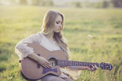 Free Woman Playing Brown Wooden Acoustic Guitar during Daytime Stock Photo