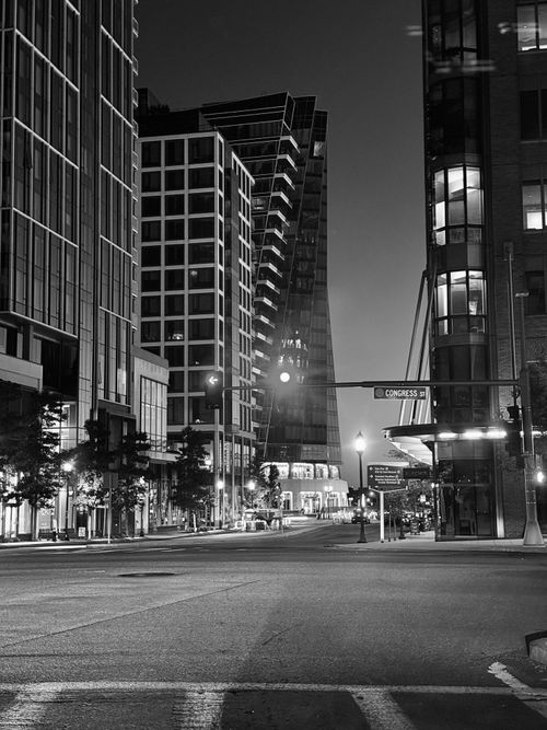 Free Black and white photo of an urban street with skyscrapers at night, showcasing modern architecture. Stock Photo