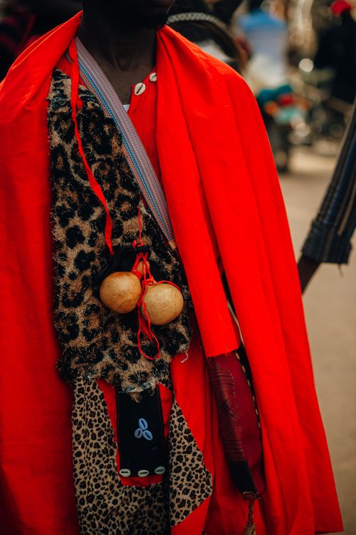 Free Close-up of traditional attire with vibrant red cloak and leopard print details in outdoor setting. Stock Photo